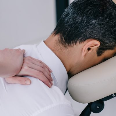 close-up shot of professional masseuse doing seated massage for businessman