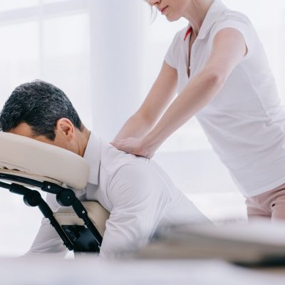 masseuse doing seated back massage for businessman at office