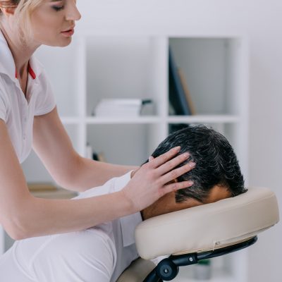 side view of masseuse doing head massage for businessman